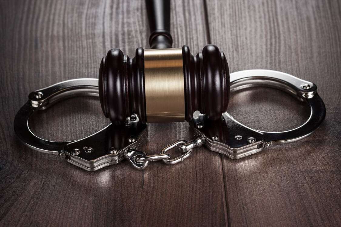 handcuffs-and-judge-gavel-on-brown-wooden-table-ptf5j2j-min